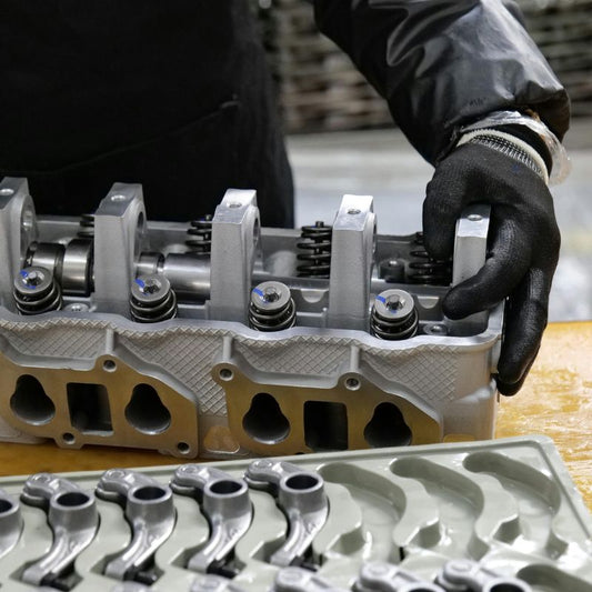 A person handling metal engine parts.