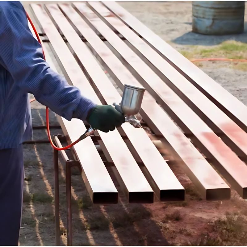 A person spraying a Cortec product on metal bars for rust prevention.