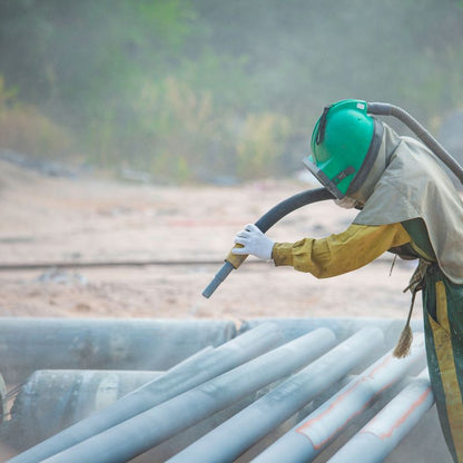 A person cleaning metal pipes by water blasting.