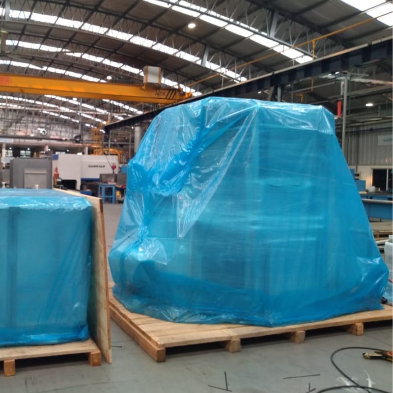 Large equipment in a warehouse wrapped in Cortec VpCI-126 Blue Film for rust prevention.